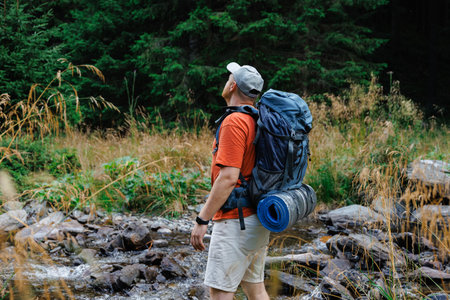 Hiker standing on stones by stream in mountainsの写真素材
