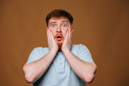teenage guy looks surprised and amazed as he strikes a pose in front of the camera in a studio