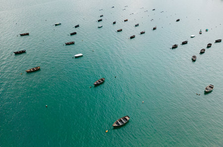 A peaceful scene with multiple boats floating on calm, clear blue water under a serene skyの写真素材