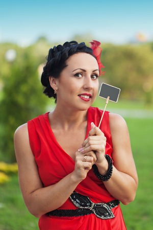 Portrait of a beautiful sexy fashion girl in a red dress on the nature of the park, with dark hairの写真素材
