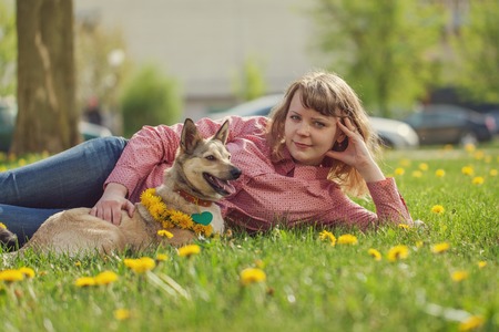 Woman with dog lying on the green grass in the parkの写真素材