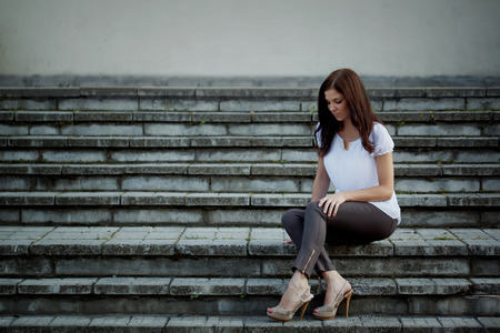 Young thoughtful woman sitting in stone stairs.の写真素材