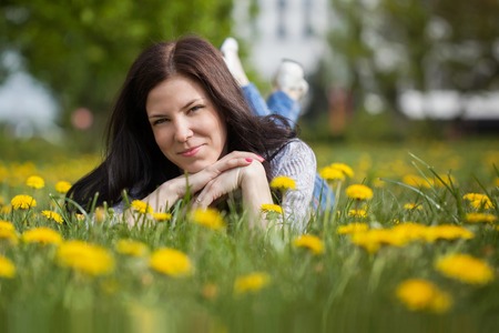 pretty woman lying down on dandelions field, happy cheerful gir.の写真素材