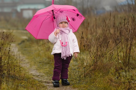 the little girl under an pink umbrella in the fall.の写真素材