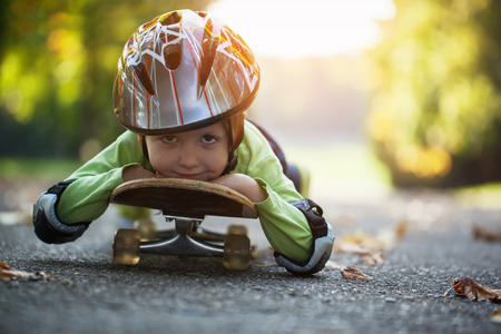 little boy having fun with skateboard in the helmet outdoors in the autumn.の写真素材
