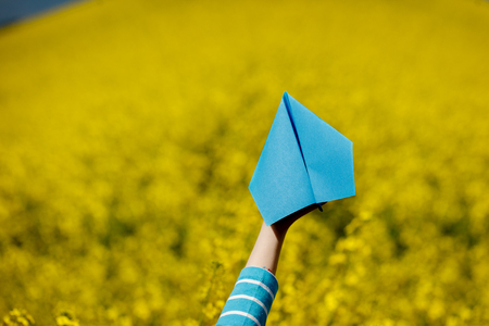 Paper airplane in children hands on yellow backgroundの写真素材