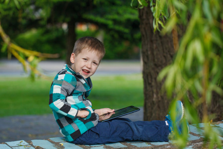 Little smile  boy outdoors  using his tablet computer. Educating and playing.の写真素材