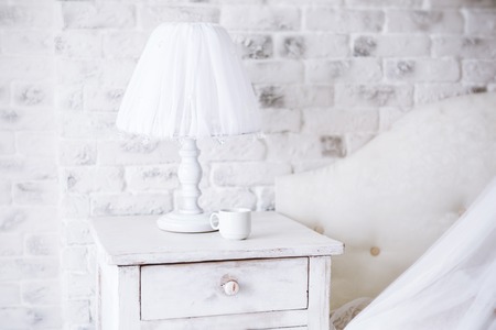 Interior Home. White lamp and  cup of coffee on a bedside table in a bedroom in early  morning.の写真素材