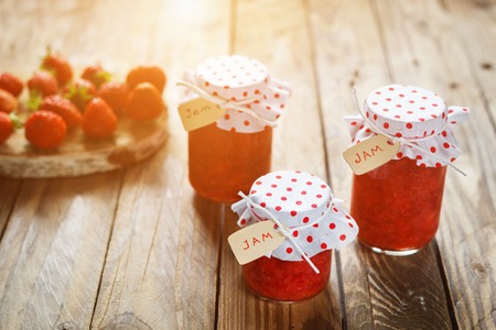 Fresh strawberry homemade jam in jar on wood background. healthy organic and vegan food. Sunlight morning.の写真素材
