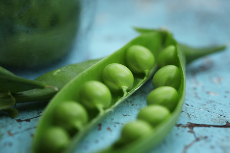 Close-up of fresh green pea on blue wooden background.の写真素材