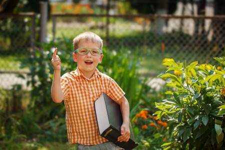 Portrait  Happy little boy holding a big book  on his first day to school or nursery. Outdoors, Back to school conceptの写真素材