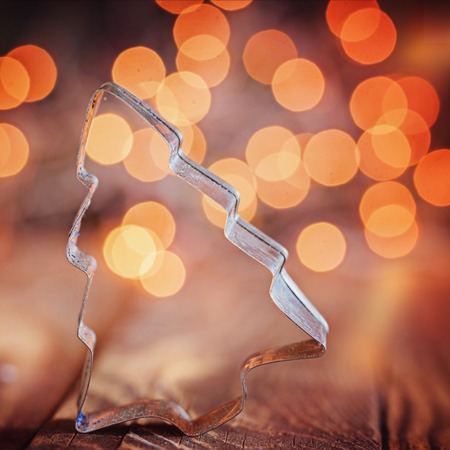 Metallic forms for preparation of christmas cookies on wooden background with a bokeh. Christmas tree. Toned imageの写真素材