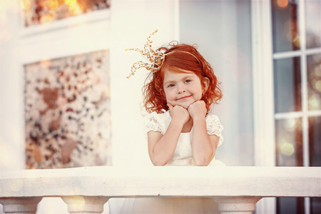Portrait of happy little beautiful girl with red hair wearing crown. Beautiful little princess.の写真素材