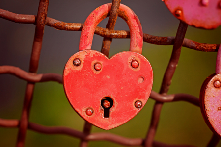beautiful red heart-shaped padlock locked on iron chain.の写真素材