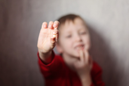 Little boy showing his first lost milk-tooth in his hand. Closeup