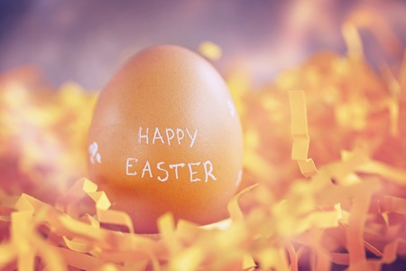 Brown Easter egg with text Happy Easter on yellow  background. Toned image.の写真素材