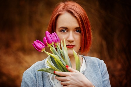 sensual red girl  with some spring flowers in park.の写真素材