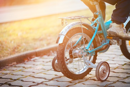 Child on a bicycle at asphalt road in sunny day. Back view.の写真素材