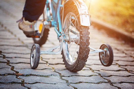 Child on a bicycle at asphalt road in sunny day. Back view.の写真素材