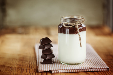 Milk yoghurt with chocolate tower on a wooden background, simple rustic styleの写真素材