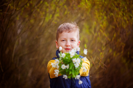 Portrait boy stretches a bouquet of spring flowers.の写真素材