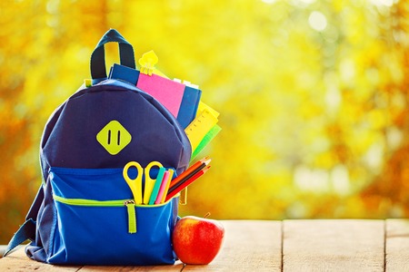 Full School backpack on wooden and autumn nature background.の写真素材
