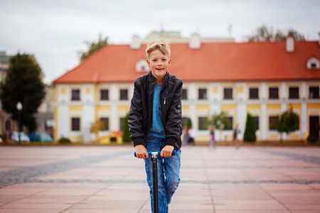 Portrait of happy little child, enjoy riding scooter on the street in the countryside in dayの写真素材