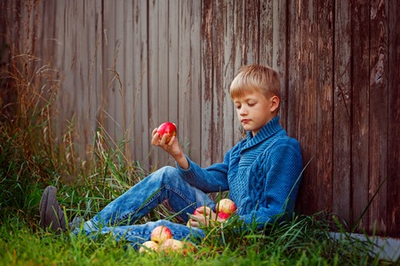 A child eating an red  apple outside in the garden.の写真素材