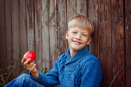 Portrait of happy boy eating an apple outside in the outdoorsの写真素材