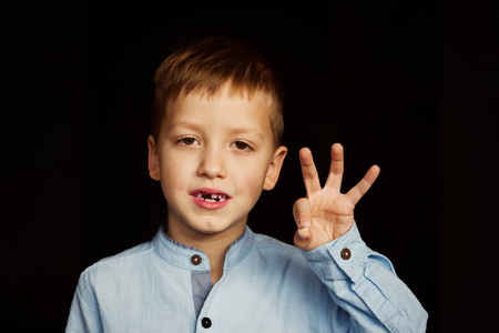 Little smiling child, boy hand showing his first milk or temporary teeth fall out