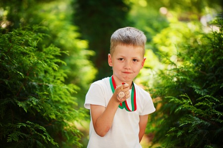 Adorable boy, holding and showing medals ad Sport Dayの写真素材