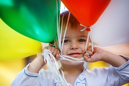 Closeup Portrait Happy child with colorful toy balloons in summer sunny dayの写真素材