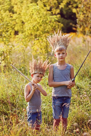 Two Brothers have a crown from dry grass on the head and swords in hands. Joy and play conceptの写真素材