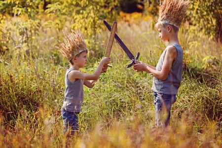 Two Brothers have a crown from dry grass on the head and swords in hands. Joy and play conceptの写真素材