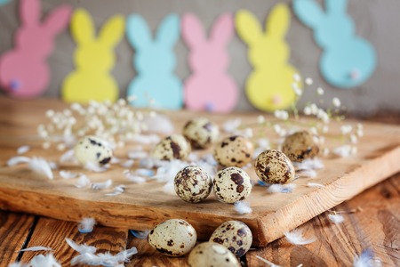 Easter composition of Easter quail eggs in the basket and with bunny garland on wooden background....