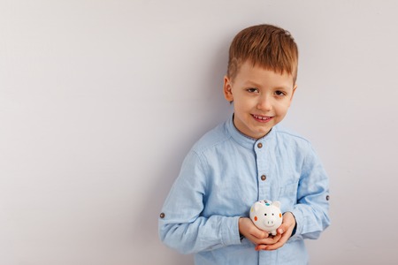 Cute little boy holding a piggy bank or money boxの写真素材