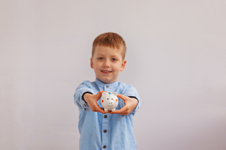 Cute little boy holding a piggy bank or money box.の写真素材