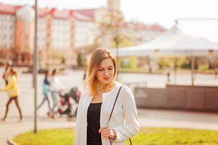 Portrait of cute girl smiling to camera in city on bulding background in sunny day.の写真素材