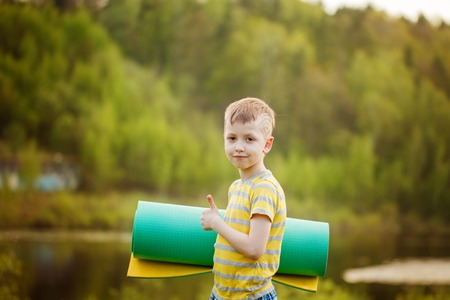 Cute boy doing sports on nature background. Sporty little boy doing exercises in the summer park. Lifestyle and sport concept.の写真素材