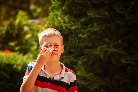 Schoolboy playing with fidget hand spinners in summer day. Popular and trendy toy for children and adultの写真素材