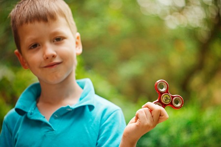 Cute little boy playing with fidget hand spinner in summer day. Popular and trendy toy for children and adult.の写真素材