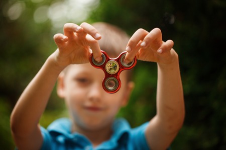 Cute little boy playing with fidget hand spinner in summer day. Popular and trendy toy for children and adult.の写真素材