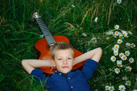 Portrait Teenage boy lying on grass with his acoustic guitarの写真素材