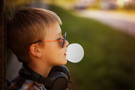 Teenage boy in sunglusses with bubble gum in summer sunsetの写真素材