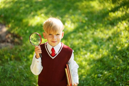CCute boy going back to school. Child with books and loupe on first school day.の写真素材