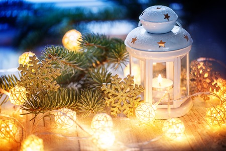 Christmas decoration with white candle lantern, fir tree branches and light garland.の写真素材