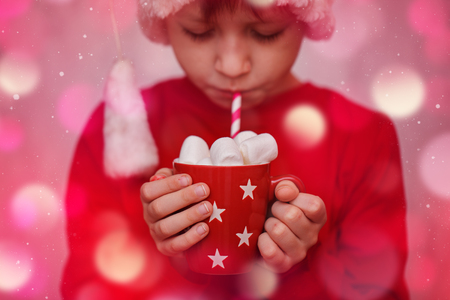 Child hands holding red cup of hot cocoa or chocolate with marshmallow. Christmas concept.の写真素材