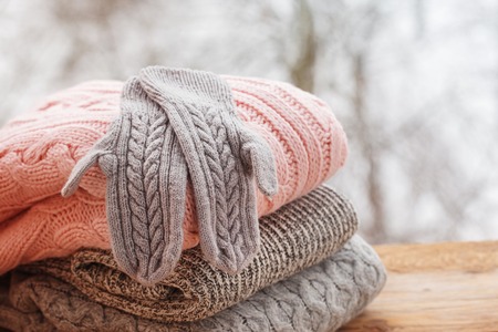 Stack of knitted sweaters on wooden tableon winter nature background.の写真素材