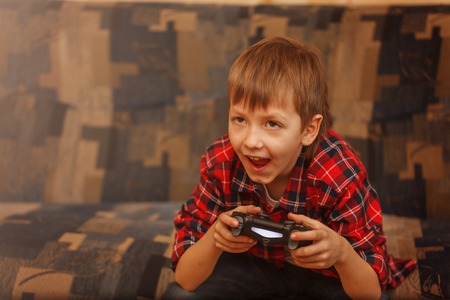 Young boy holding gamepad and playing video games.