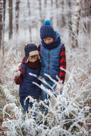 Two brothers on walr in winter forest. Best friends playing together.の写真素材